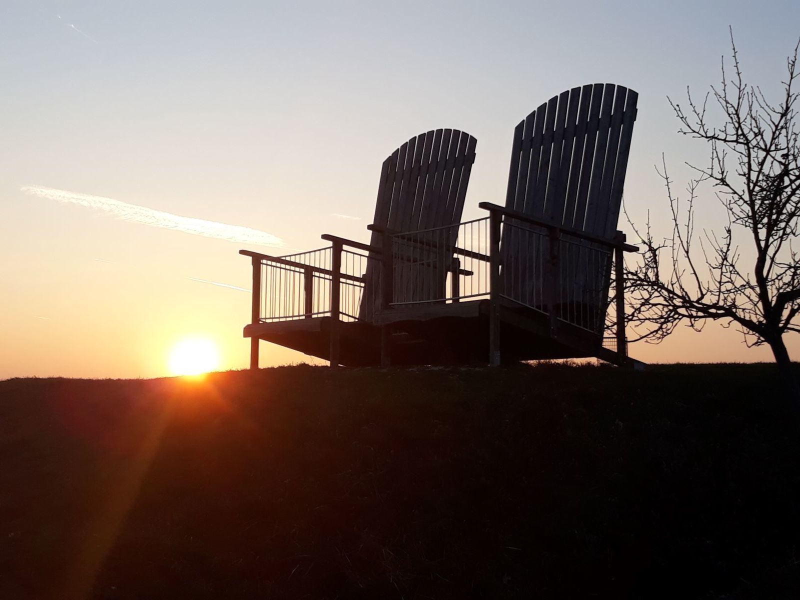 Zwei große Holzstühle als Silhouette im Sonnenuntergang