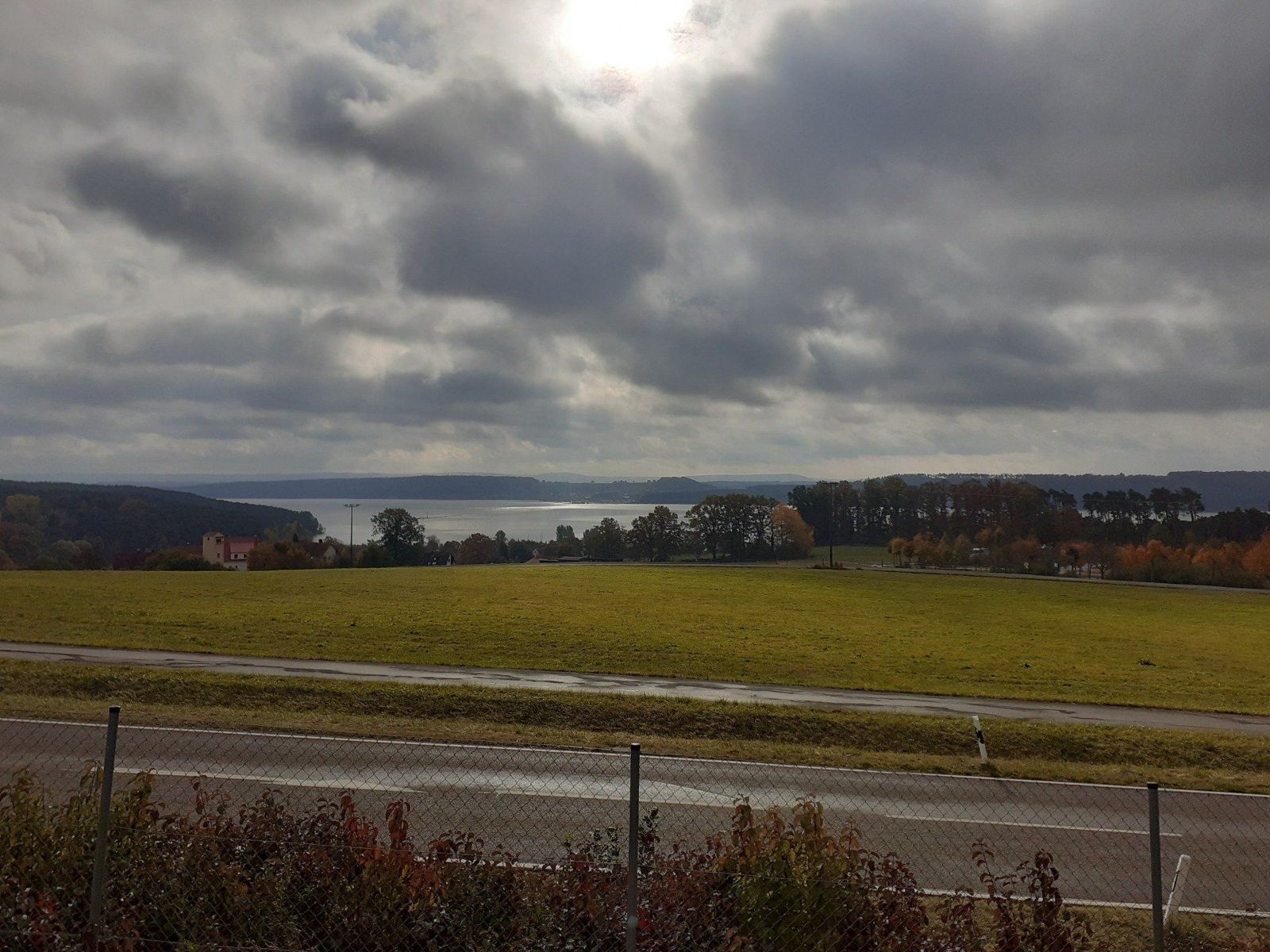Bewölkter Herbsttag mit Blick über Wiesen zum See