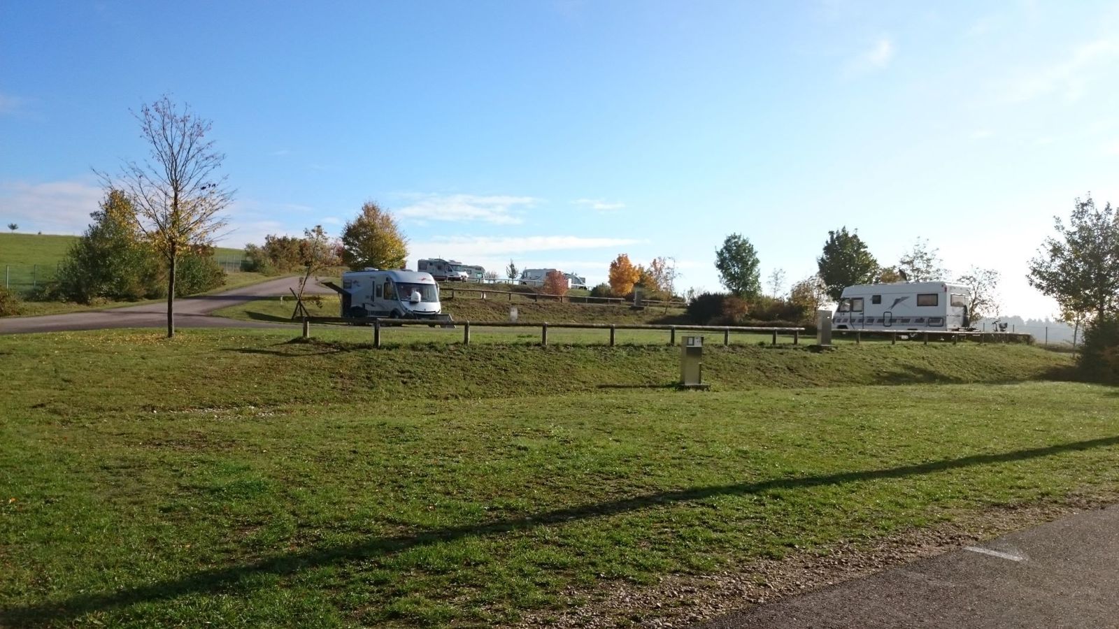 Stellplatzgelände im Herbstlicht mit Wohnmobilen und Bäumen